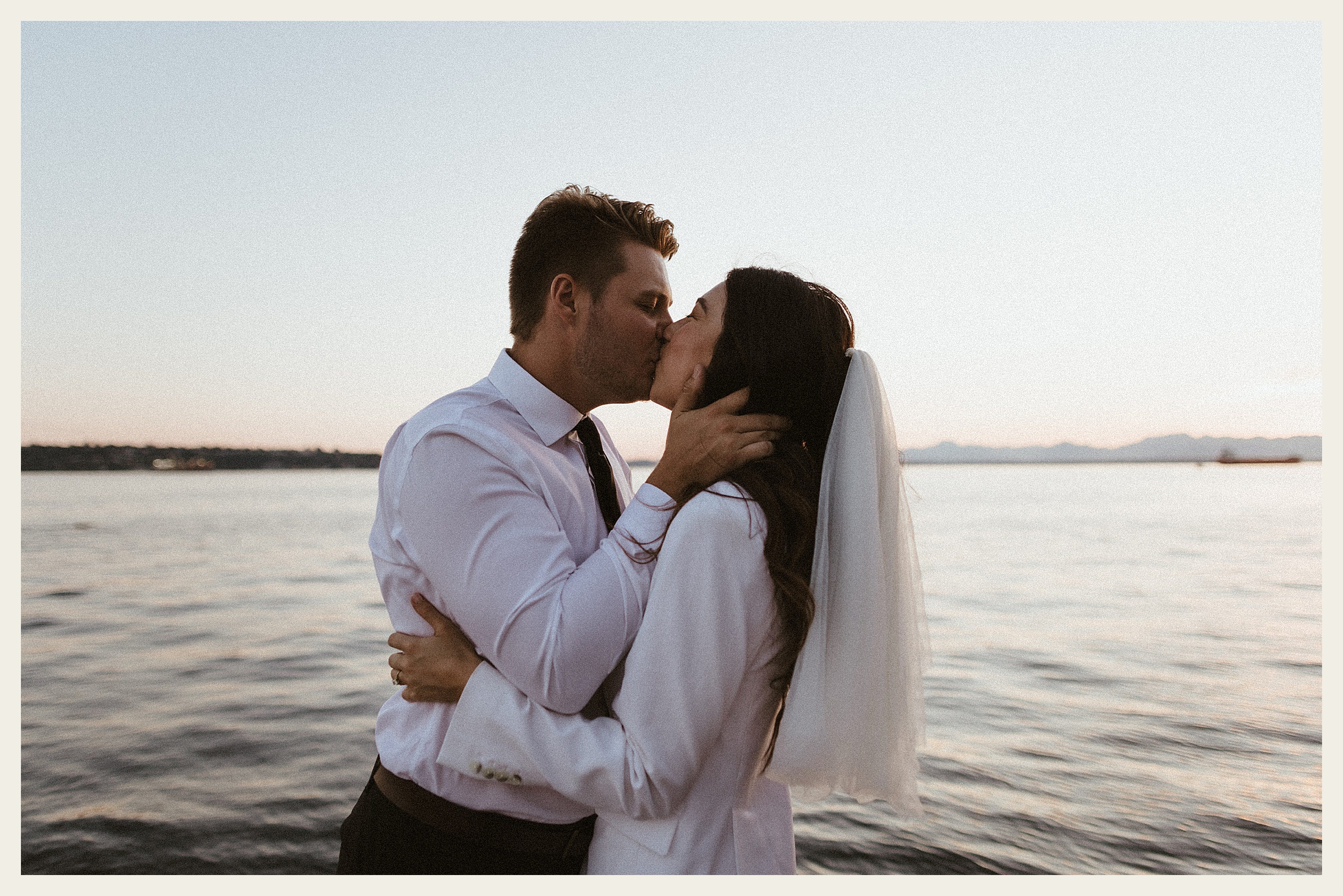 bride and groom kissing by water