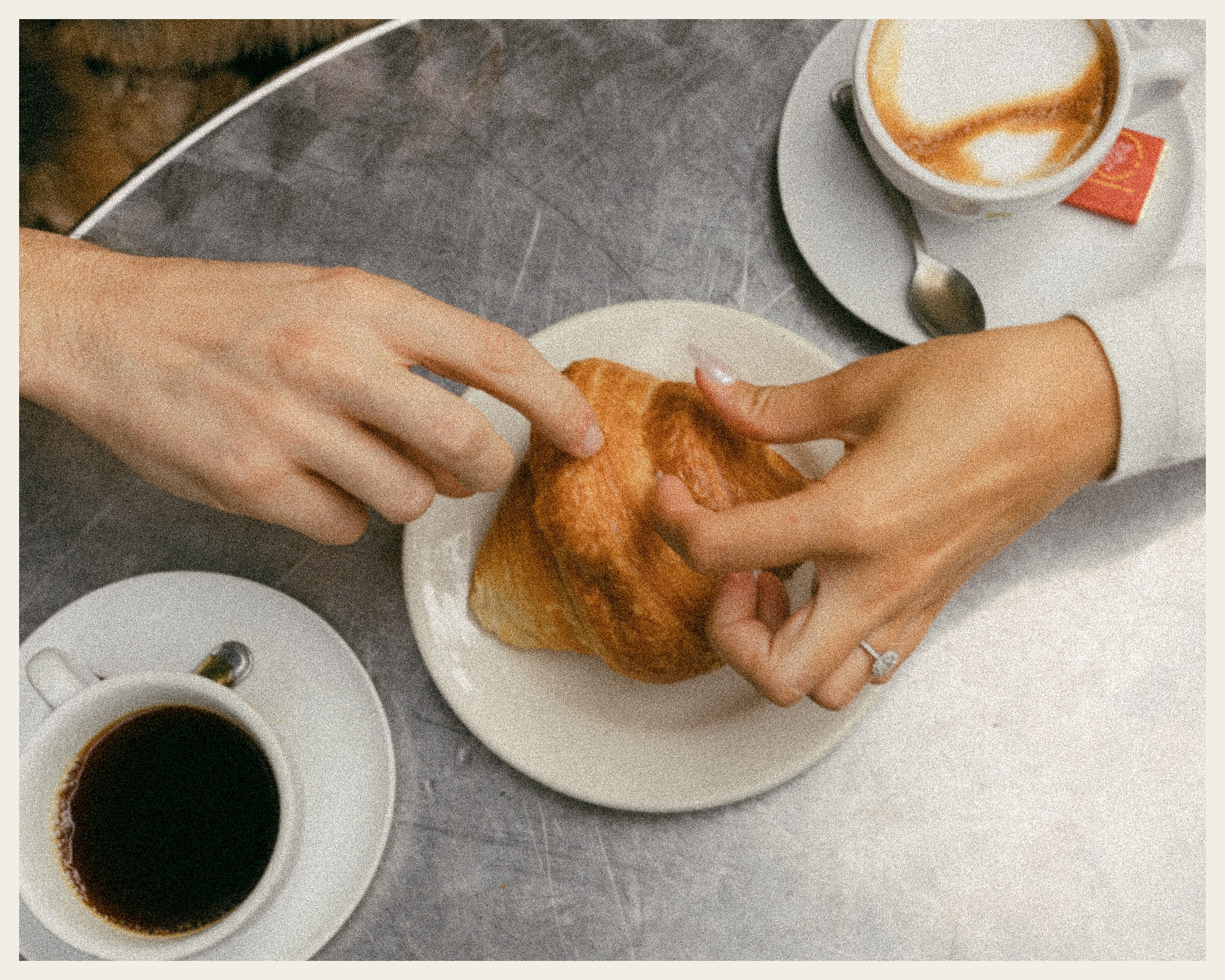two hands picking at croissant