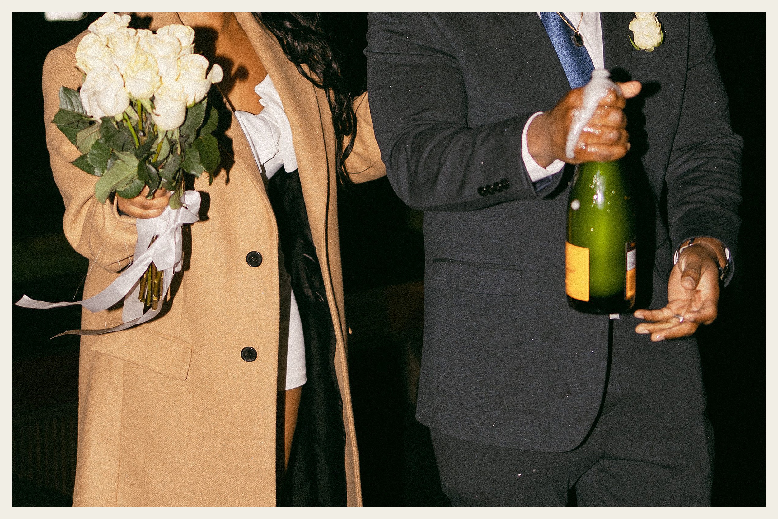 bride and groom holding champagne bottle